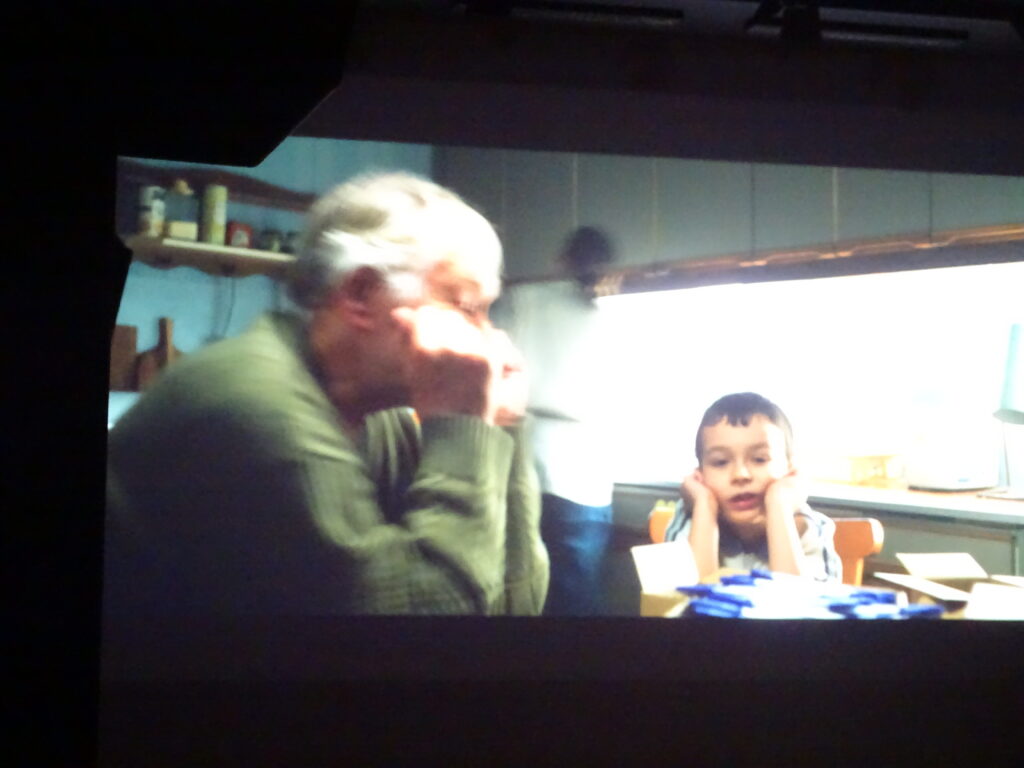 Kadr z filmu- chłopiec siedzi przy stole ze starszym panem,