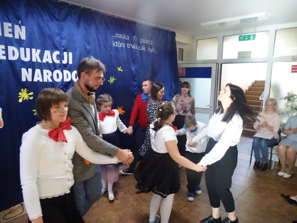 Wychowankowie wraz z nauczycielami w kole tańczą do piosenki „Witajcie w naszej bajce”. Wraz z dziećmi tańczy Pan Kleks. 