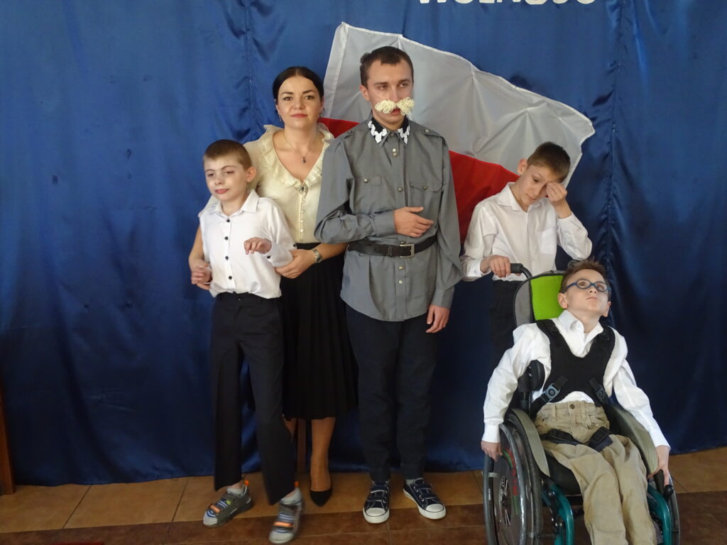 Pani Kasia jako Aleksandra Piłsudska i Krystian jako Józef Piłsudski wraz z Adasiem , Danielem i Tomaszkiem  na tle flagi .